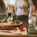 a group of women stand around a table with food