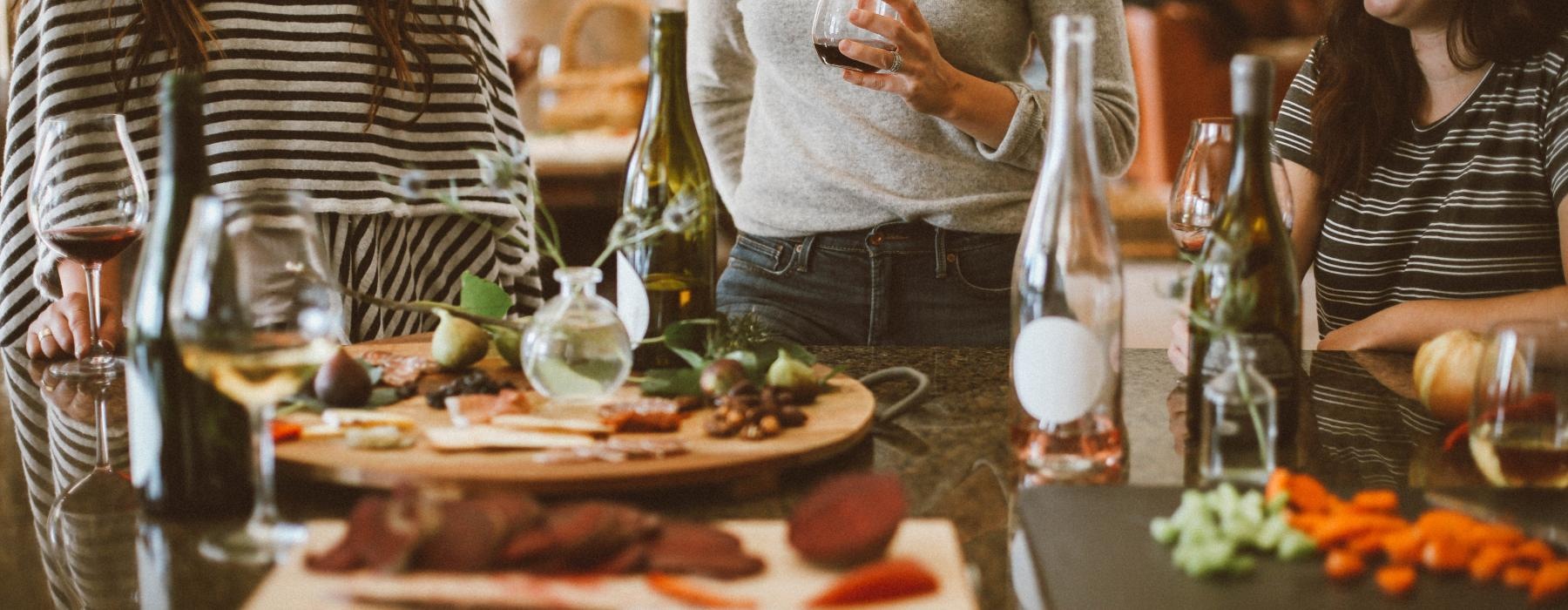 a group of women stand around a table with food