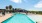 a swimming pool with chairs and a house in the background