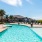 a swimming pool with chairs and a house in the background